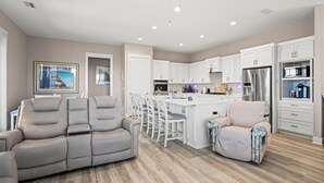 A modern kitchen with white cabinets, a stainless steel refrigerator, and a microwave. - Beach House - Magical Purple Haze (Mexico Beach)