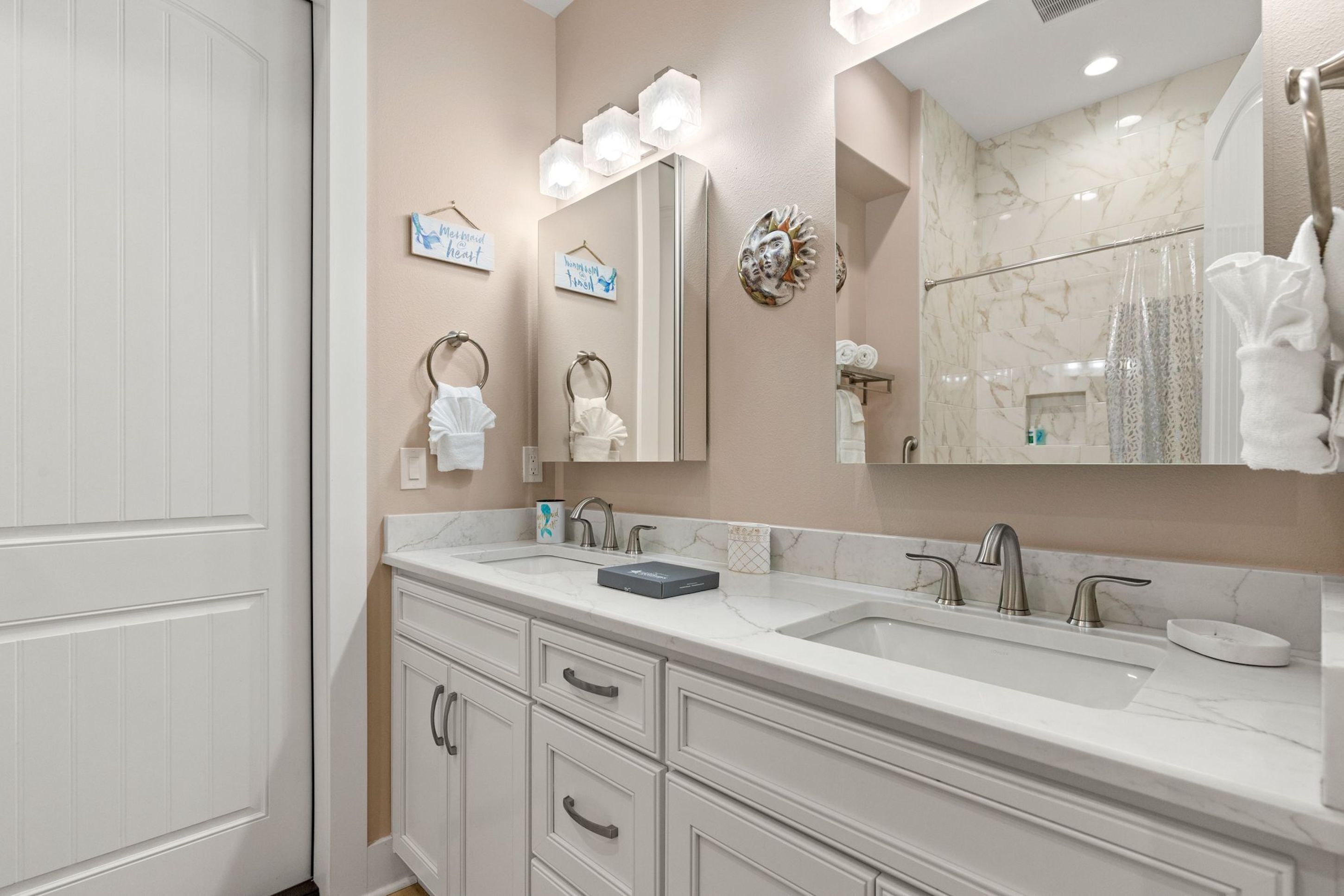 A modern bathroom with two sinks, a large mirror, and a vanity with drawers.
