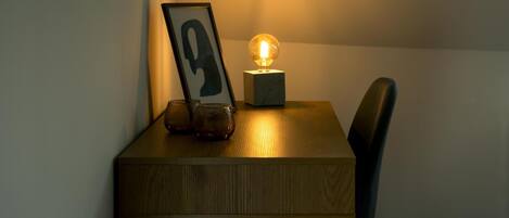 A wooden table with a framed picture, a glass, and a spherical light fixture.