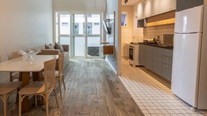 A modern kitchen with a dining area, large windows, and a view of the city.