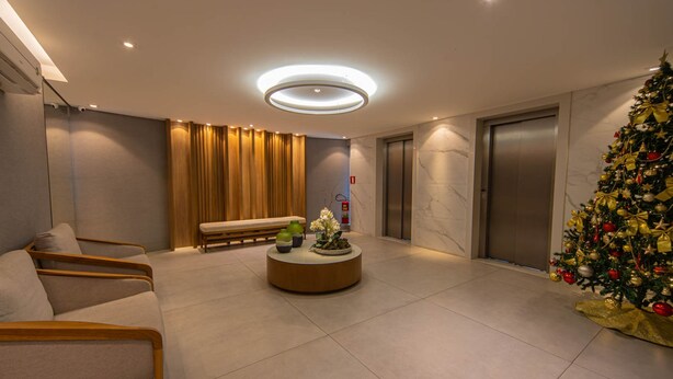 A modern lobby with a round coffee table, seating area, and a Christmas tree.