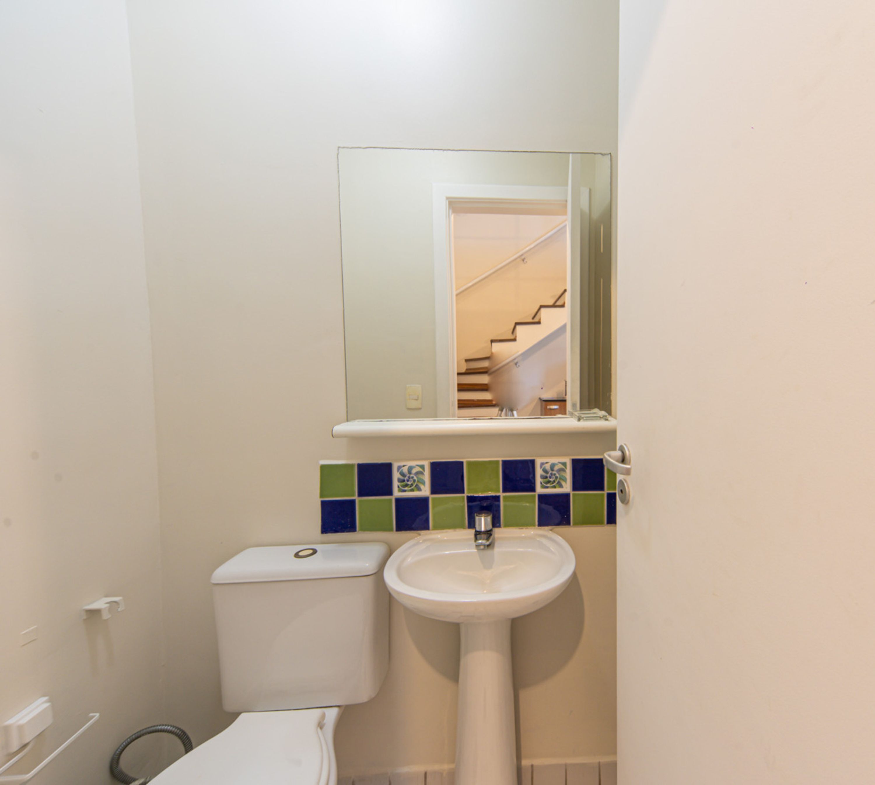 A bathroom with a toilet, sink, and a mirror above the sink.