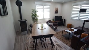 Een moderne woonkamer met een houten eettafel, een bank, een televisie en een open haard.