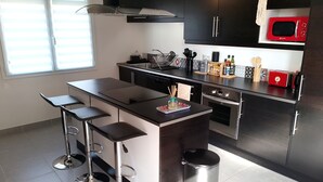Een moderne keuken met een centraal eiland, barstoelen, een magnetron en een oven.