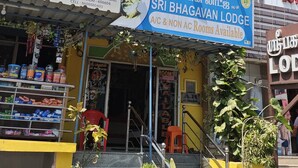 Un edificio con varios letreros, incluyendo 'Sri Devi Medicals' y 'Sri Bhagavan Lodge', donde hay habitaciones con aire acondicionado y sin aire acondicionado.