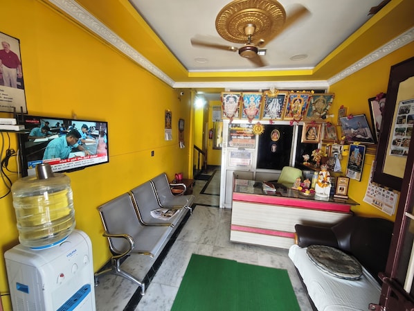 A reception area with a television, seating, a water dispenser, and a counter with religious items.