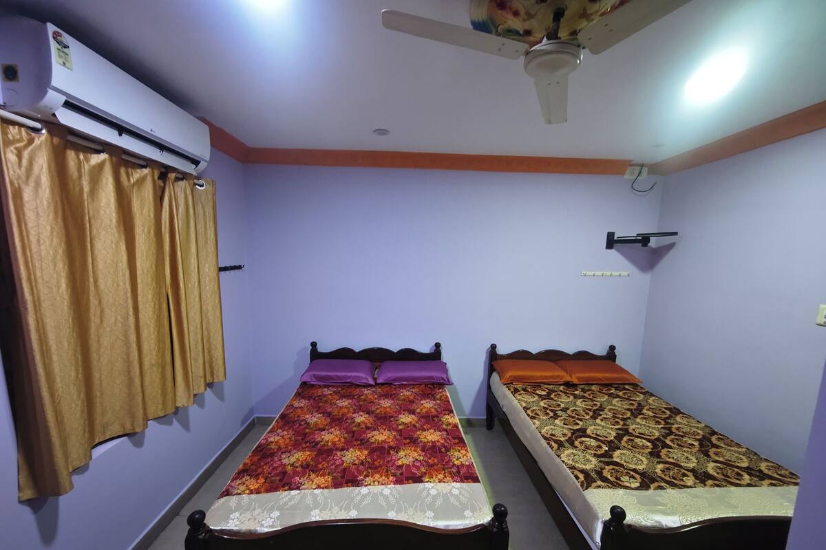 A bedroom with two beds, a ceiling fan, and an air conditioning unit.