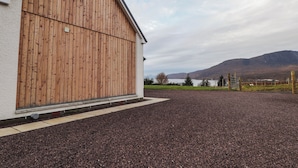 Ett stort trälada med vitmålad fasad, beläget vid en grusuppfart med en vacker bergskedja som bakgrund.