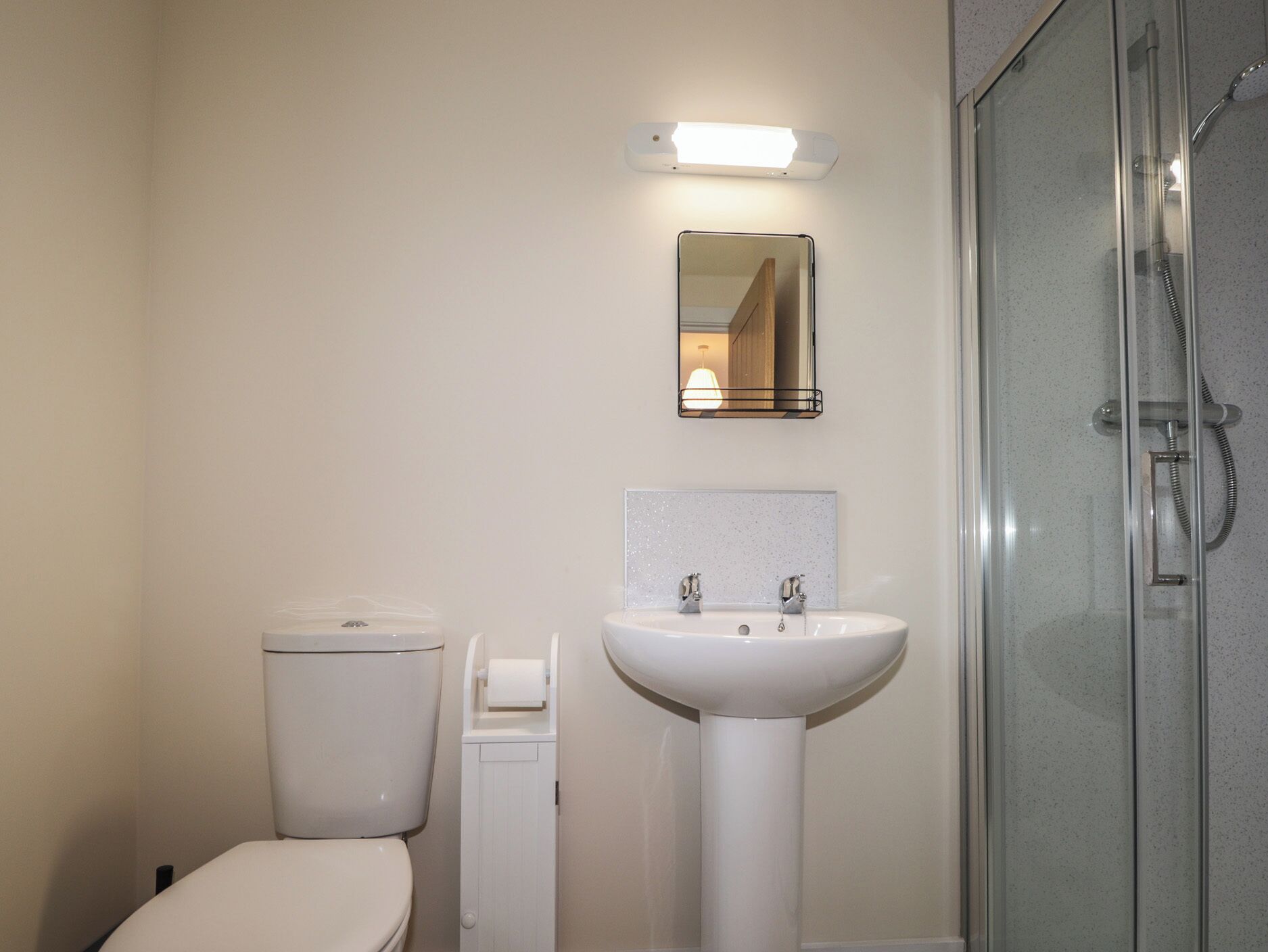 A bathroom with a toilet, a sink, and a glass-enclosed shower.