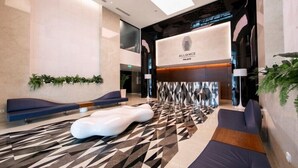 A modern lobby with a geometric patterned floor, seating areas, and a reception desk with the 'Alliance Place' sign. - Studio by Alliance (Batumi)