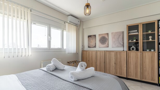 Une chambre à coucher avec un grand lit, une armoire et une fenêtre équipée de stores.
