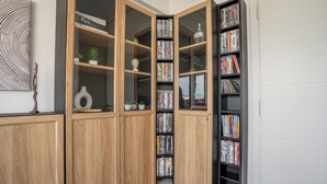 Une pièce d’angle avec une armoire en bois contenant des livres et des objets décoratifs, une petite plante et un vase.