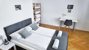 A neatly arranged bedroom with a bed, bedside table, and a desk with a chair. - Bright Apartment with Balcony | Workspace (Wrocław)
