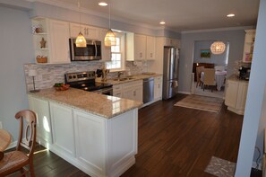 A modern kitchen with white cabinetry, granite countertops, stainless steel appliances, and pendant lighting. - Large RBYCC Home located 2 miles to the beach! (Rehoboth Beach)