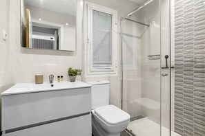 Uma casa de banho com sanita, lavatório e chuveiro.