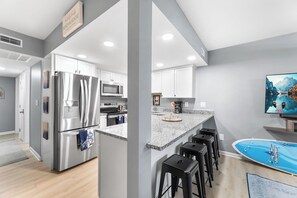 Eine moderne Küche mit Edelstahlgeräten, einer Granitabdeckung und einer Bar mit Hockern.