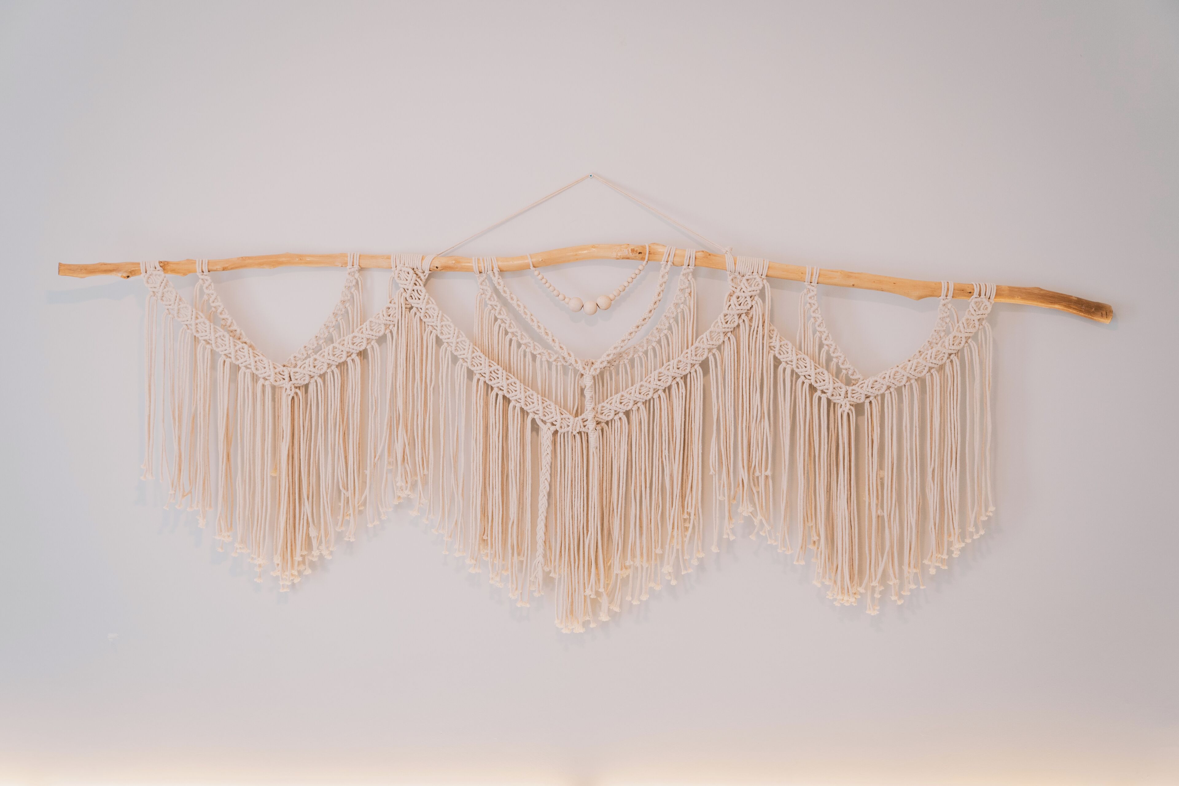 Un tapiz de macramé con un colgador de madera.