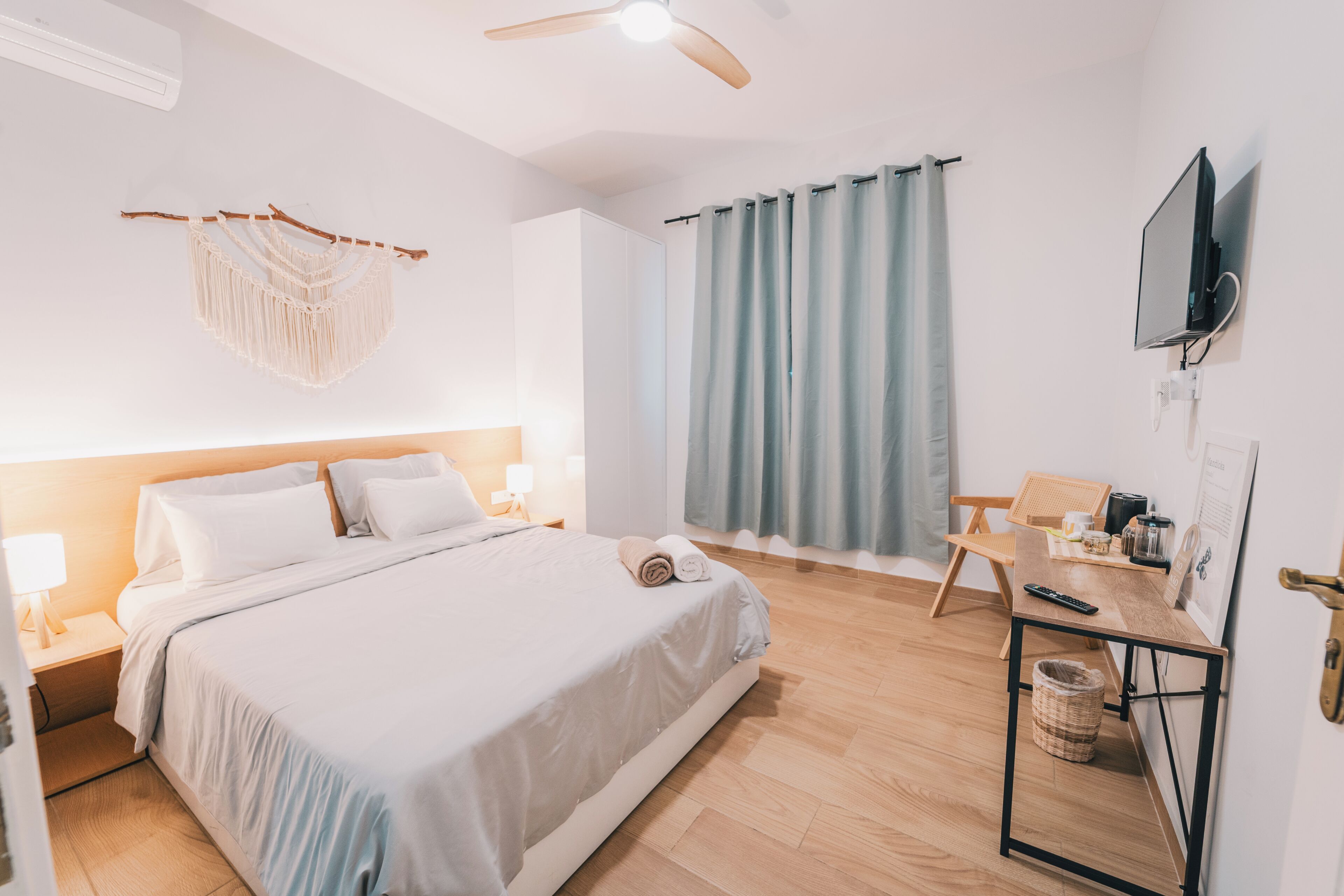 A bedroom with a bed, bedside table, lamp, and a TV mounted on the wall.