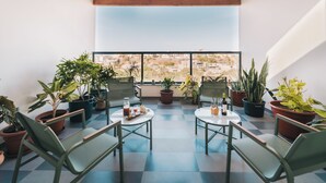 A terrace with potted plants, seating, and a city view. - Casa Jardim di Sol (Praia)