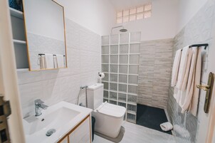Un baño moderno con lavabo, inodoro, ducha y cabina de ducha con paredes de vidrio.