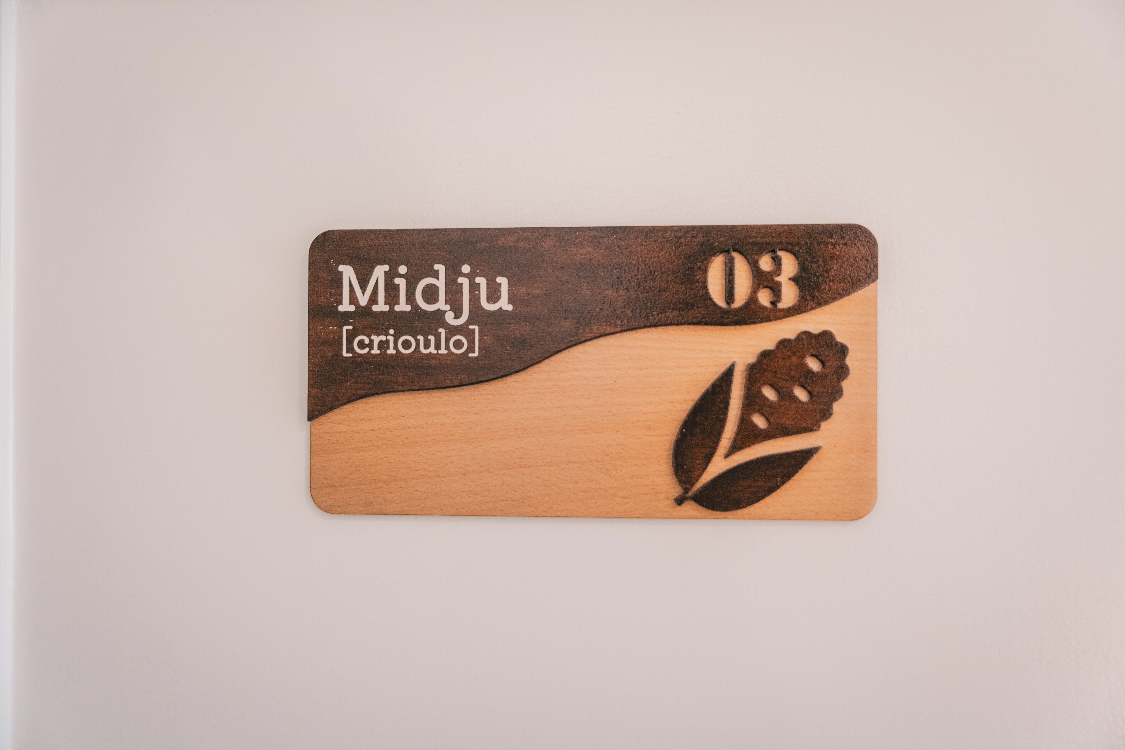A wooden plaque with the text 'Midju [crioul]' and the number '03'.