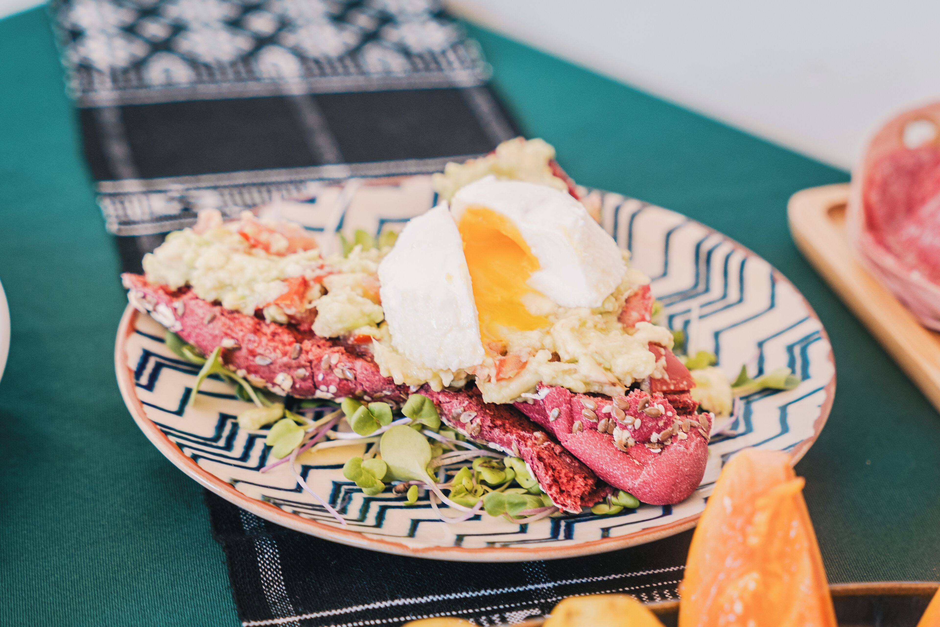 Un plato de comida con un huevo pochado, patatas ralladas y verduras sobre un plato estampado.