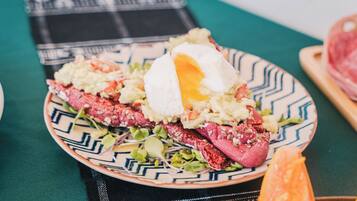 Un plato de comida con un huevo pochado, patatas ralladas y verduras sobre un plato estampado.