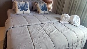 A modern bedroom with a large bed, a headboard with vertical slats, and a window with curtains.