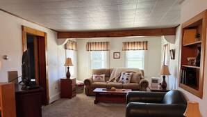 A living room with a sofa, a coffee table, a TV, and a bookshelf. - The Minor House - A Cozy Stay in Shullsburg WI (Shullsburg)