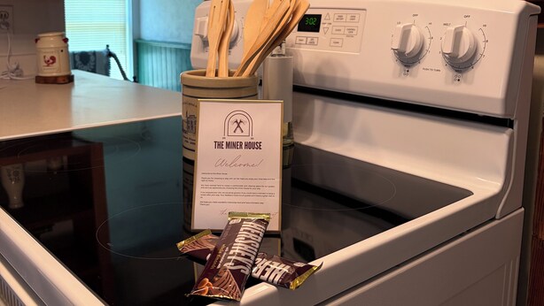 A kitchen with a stove, a sign reading 'The Miner House,' and a bag of chips on the counter. - The Minor House - A Cozy Stay in Shullsburg WI (Shullsburg)