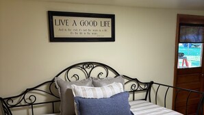 A bed with a white and blue striped bedspread, a framed quote on the wall, and a window with a view of a vehicle outside. - The Minor House - A Cozy Stay in Shullsburg WI (Shullsburg)