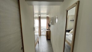 A narrow hallway with a bed and a desk in the distance, leading to a balcony. - Studio with pool access and views of the Diamond Rock and Morne Larcher (Le Diamant)