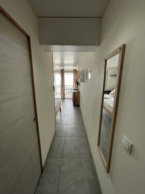 A narrow hallway with a bed and a desk in the distance, leading to a balcony. - Studio with pool access and views of the Diamond Rock and Morne Larcher (Le Diamant)