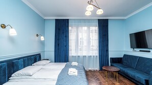 A hotel room with a bed, a sofa, a TV, and a small table. - RentPlanet - Apartament Sobieskiego (Kraków)