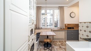 A compact kitchen with a wooden table, a built-in oven, and a radiator. - RentPlanet - Apartament Sobieskiego (Kraków)