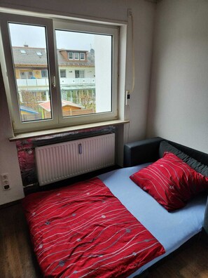 A small bedroom with a single bed, a window, and a radiator.