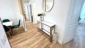 A modern interior with a wooden floor, a white console table, a green chair, and a round mirror on the wall. - Paris- 15 min – Large 5-room apartment fully renovated – Orly Airport -15 min (Vitry-sur-Seine)
