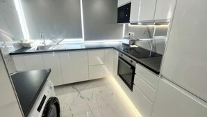 A modern kitchen with white cabinets, a black countertop, a built-in oven, and a microwave. - Paris- 15 min – Large 5-room apartment fully renovated – Orly Airport -15 min (Vitry-sur-Seine)