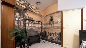 A room with a mural of a tropical landscape, a radiator, a potted plant, and a door. - Kolonaki Cozy (Athina)