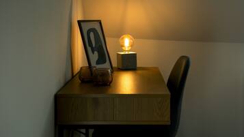 A wooden table with a framed picture, a glass, and a spherical light fixture.