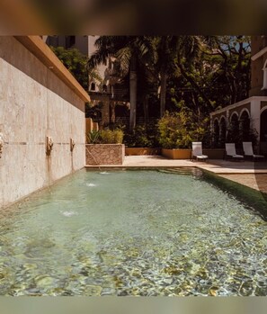 A swimming pool with clear water, surrounded by stone walls and palm trees. - Stunning 2-Story Penthouse Tamarindo Guanacaste Costa Rica. Beach 2 Min Central (Tamarindo)