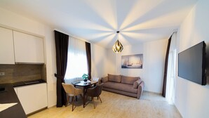 Ett kompakt bostadsutrymme med ett litet kök, en matplats, en soffa och en TV som är monterad på väggen.