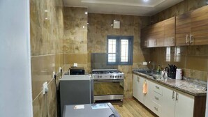 A compact kitchen with a gas stove, oven, and a washing machine. - STBJ APARTMENT (Abuja)