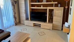 A living room with a TV, wooden cabinet, and a statue. - Holiday Home 'Lechseeidylle' in Elevated Edge Location with 'Königscard' Benefit (Lechbruck am See)