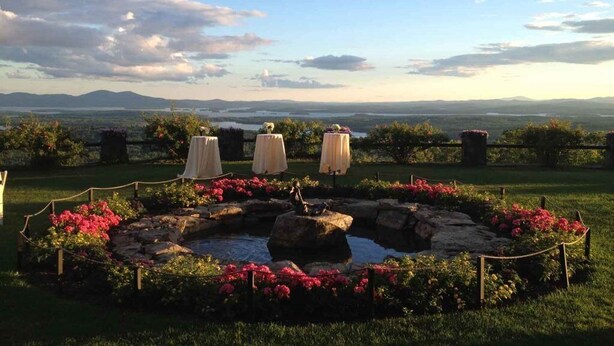 A garden with a pond, surrounded by flowers and a view of distant mountains.