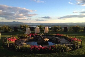 A garden with a pond, surrounded by flowers and a view of distant mountains.
