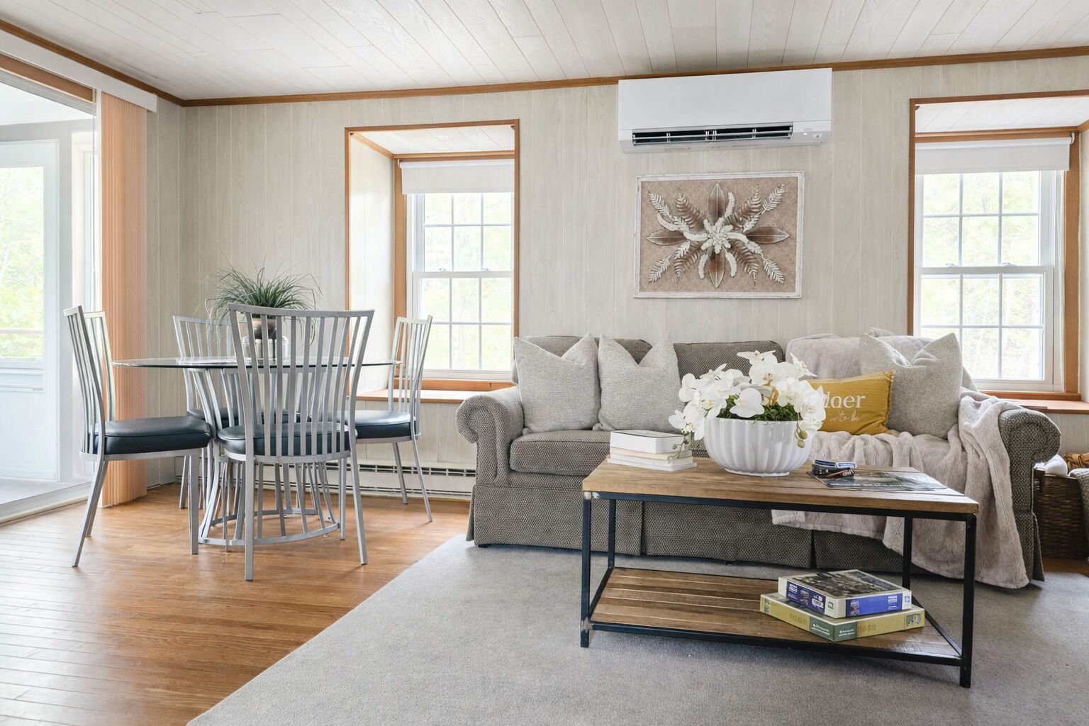 A living room with a sofa, coffee table, and dining area with chairs.