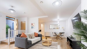 A modern living room with a grey sofa, wooden coffee table, and a large potted plant. - The Albany Sleeps 2 With Wifi (Redhill)