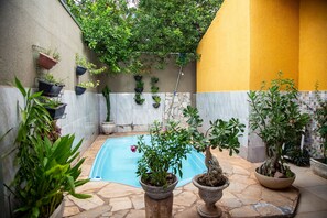 A pool area with potted plants and a tiled floor.