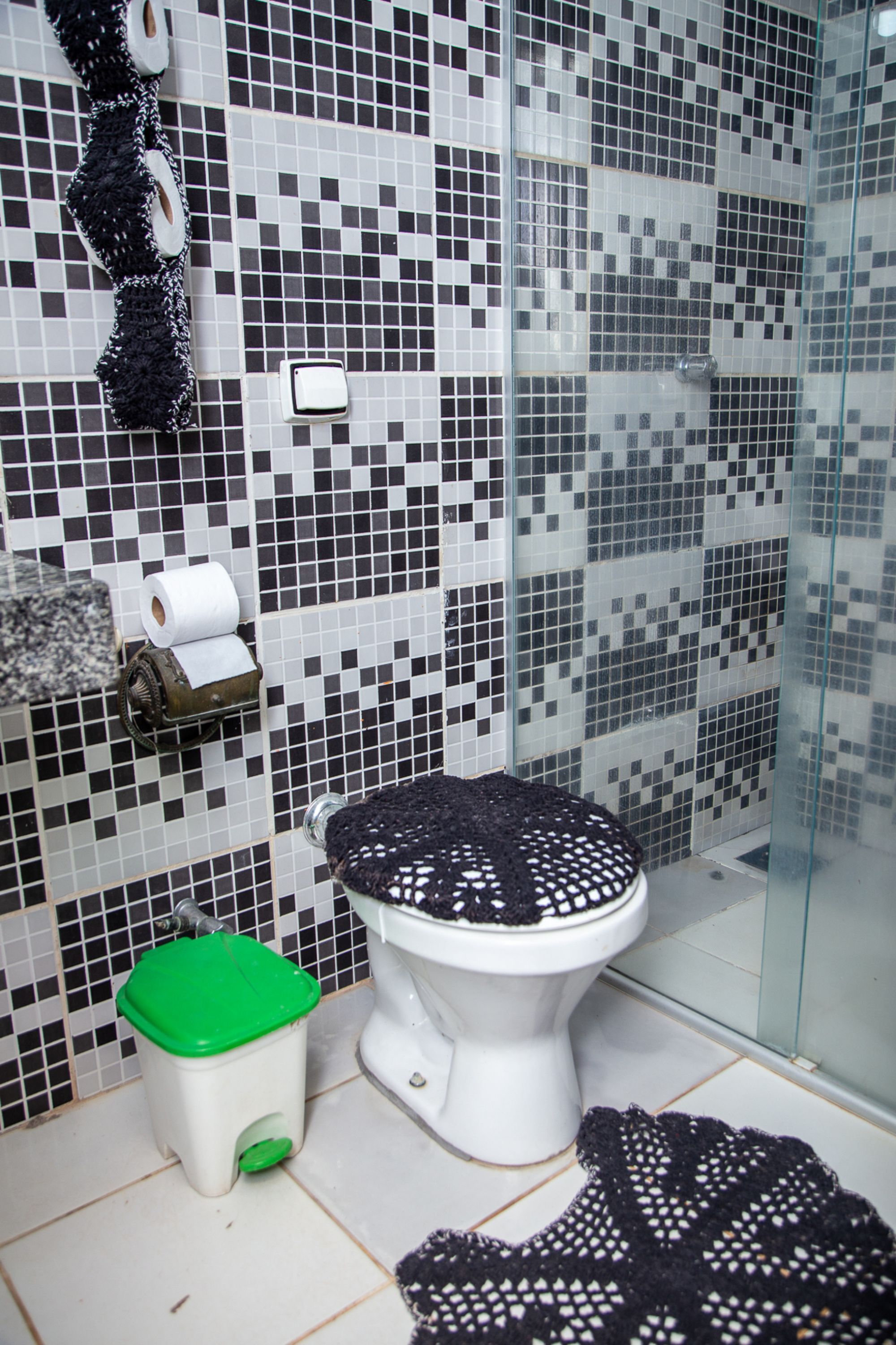 Ein Badezimmer mit Toilette, einem grünen Mülleimer und einem gemusterten Teppich.
